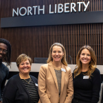 The CFJC Team (left to right, Aaron Gumm Jr, Julie Yoder, Shelly Maharry, Anne Barber, Ellie Moore) posing for a photo inside North Liberty City Hall's council chambers